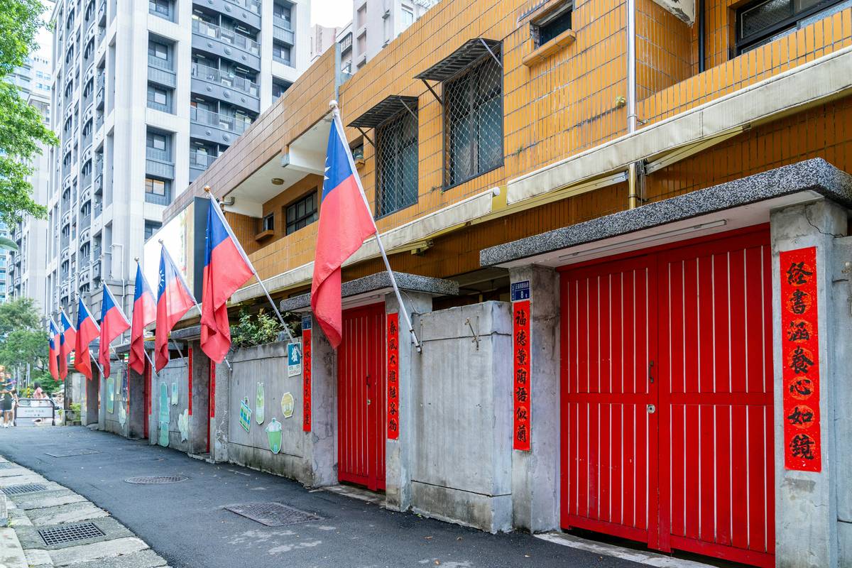 Several taiwanese flags displayed outside red doors.